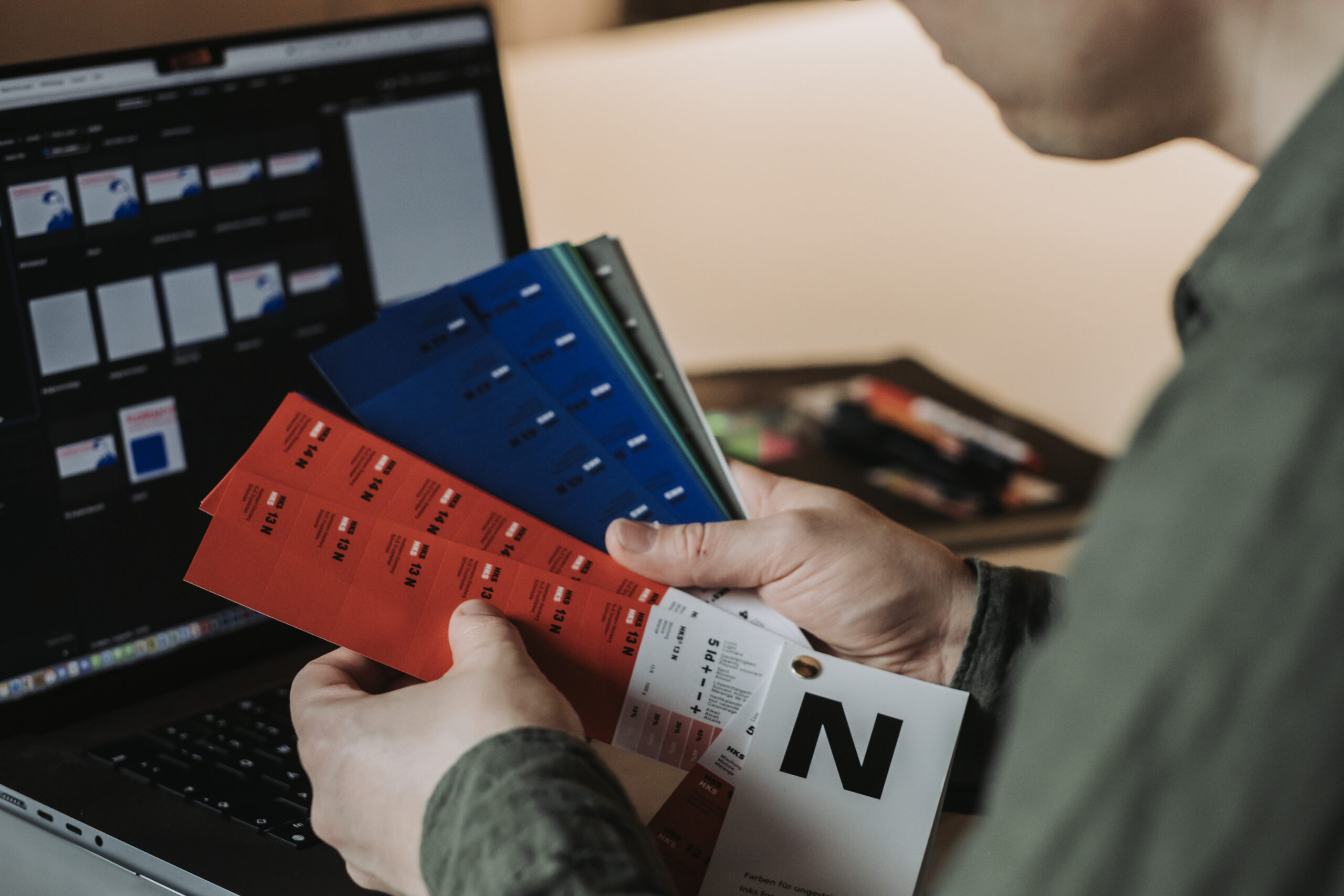 Florian Hucht Personal - Wie ich arbeite Designer schaut in HKS-Farbfächer- man sieht die Farben Rot und Blau